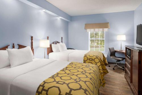 a hotel room with two beds and a television at Baymont by Wyndham Henderson Oxford in Henderson