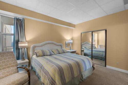 a bedroom with a bed and a chair and a mirror at Sans Souci unit 706 in Pensacola Beach