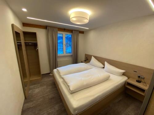 a bedroom with a large white bed with a window at Sonnleiten - Guggerhof - Villa Sonnenwies in Tannheim