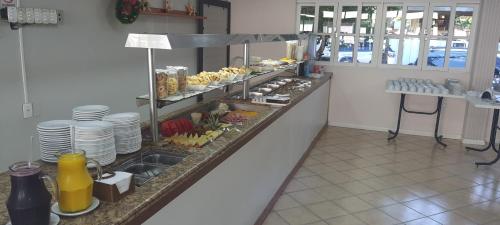 a buffet line in a restaurant with plates and food at Hotel Pousada Ilha do Mar Bombinhas in Bombinhas