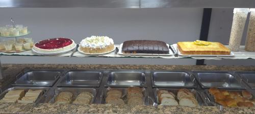 a display case with different types of cakes and pastries at Hotel Pousada Ilha do Mar Bombinhas in Bombinhas