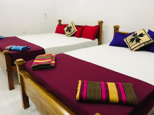 una camera con tre letti con cuscini colorati di LAKE NEST resort a Anuradhapura