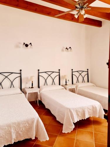 a room with three beds and a ceiling fan at Casa Ses Roques in Ciutadella