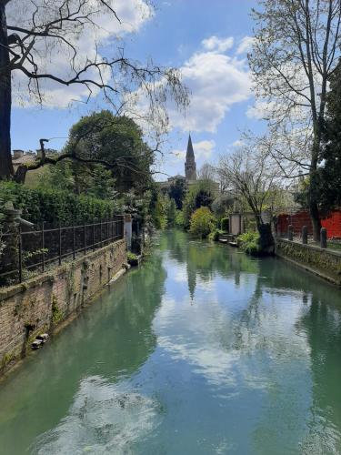 a river with green water and a church in the background at Casa di Clara in Portogruaro