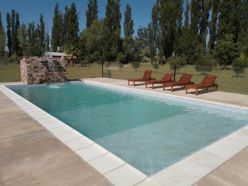 a swimming pool with two chairs and a swimming poolvisor at cabaña alojamiento Canto de las Aves in San Rafael