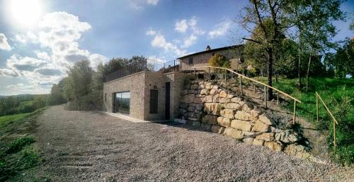 a stone house on a hill with a stone wall at Agriturismo Casa Greppo in San Venanzo