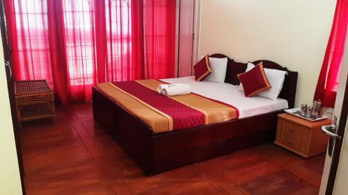 a small bedroom with a bed with red curtains at Sunrise Villa in Kodaikānāl