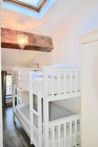 two white bunk beds in a room with a chandelier at Le Gite de la Galerie Forge in Alaigne