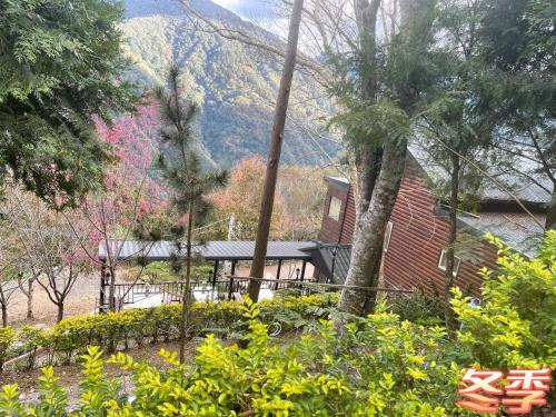 a house with trees and a mountain in the background at Lala Mountain Homestay‧Cile Farm in Hualing