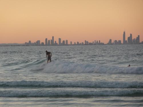 a man riding a wave on a surfboard in the ocean at Blue Pelican Motel in Tweed Heads