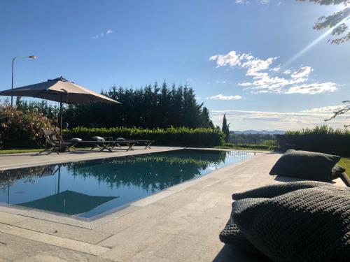 a swimming pool with an umbrella and chairs next to it at B&B Puntodivista in Chieri