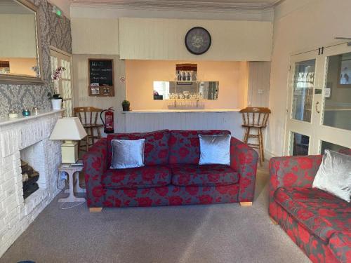 a living room with a red couch and a fireplace at Buckingham Lodge Guest House in Torquay