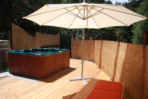 an umbrella sitting on a deck next to a hot tub at Camping Du Parc in Pré-Saint-Didier