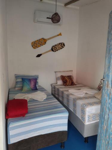 two twin beds in a room with a baseball bat on the wall at Pousada Hospedaria Nativus Caraiva in Caraíva