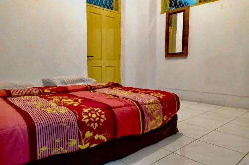 a bed with a red blanket and a yellow door at OYO 90847 Eko Guest House in Makassar