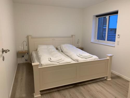 een wit bed in een kamer met een raam bij Spacious Apartment on N.P.Gøta 8a, Klaksvik in Klaksvík