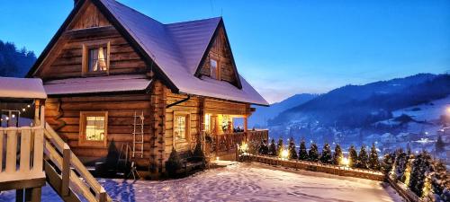 una cabaña de madera en la nieve con luces de Navidad en Chata Natura, en Muszyna