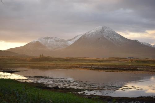 a snow covered mountain in front of a body of water at Skye Coorie Cabin in Breakish