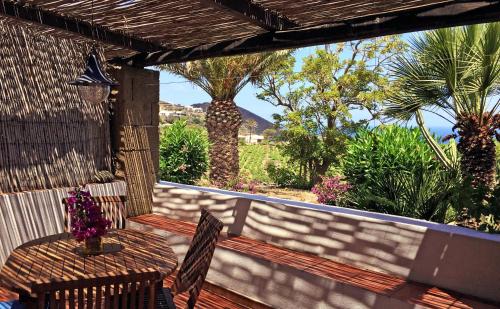 a deck with a table and chairs and palm trees at I Dammusi di Punta Karace in Tracino