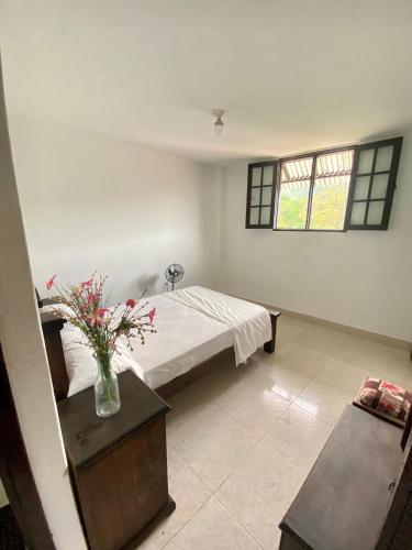 a bedroom with a bed and a vase of flowers on a table at Casa entera rústica con terraza, parque principal in San Vicente de Chucurí