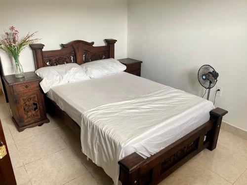 a bedroom with a large bed with white sheets and a table at Casa entera rústica con terraza, parque principal in San Vicente de Chucurí