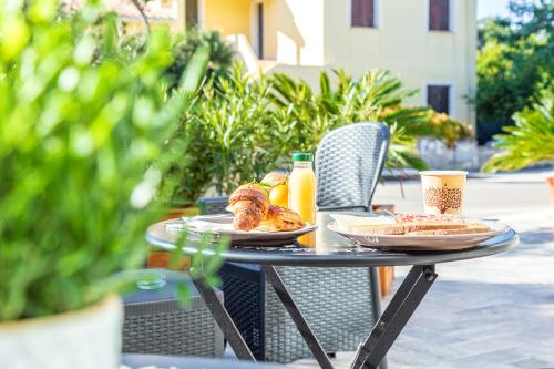 einen Tisch mit Speisen und Getränken auf einer Terrasse in der Unterkunft Acquazzurra guest house in Tortolì