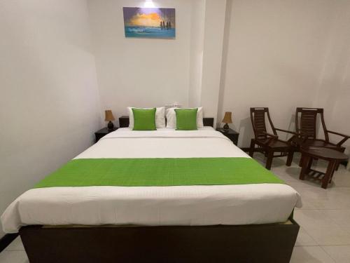 a bedroom with a large bed with green pillows at KITHULA Boutique Hotel in Hikkaduwa
