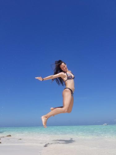 a woman jumping in the air on the beach at Ras Rana Lodge in Rasdu