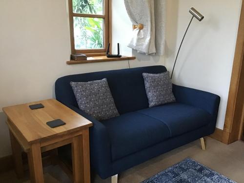 a blue couch in a living room with a table at Old Chapel Forge in Chichester