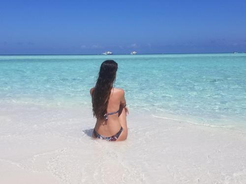 a woman sitting in the water on a beach at Ras Rana Lodge in Rasdu