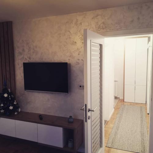 Una sala de estar con un televisor de pantalla plana en la pared. en Apartman Casa Lukavica Istočno Sarajevo, en Lukavica