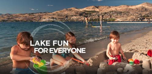a woman and two children playing in the sand on the beach at Grandview Lake Chelan- Waterfront View, Pool, Hot tub, Golf, 1 Min To Downtown in Chelan