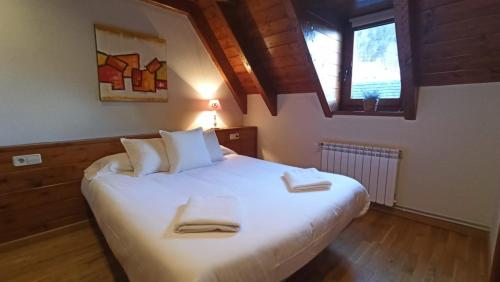 a bedroom with a large white bed with two towels on it at Tredós, Casa adosada. Baqueira in Tredós