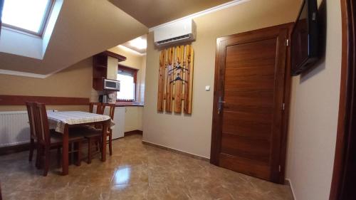 a room with a table and a door and a dining room at Nefelejcs Fagyizó és Apartmanház in Kistolmács