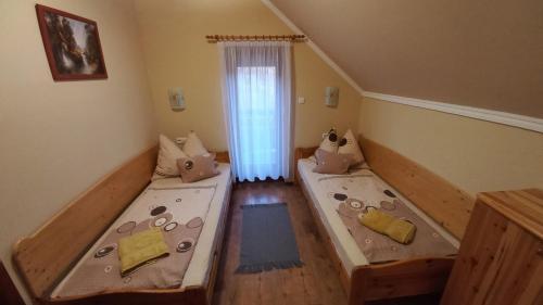 a room with two beds and a window at Nefelejcs Fagyizó és Apartmanház in Kistolmács