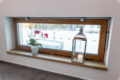 a window with a candle and a vase with flowers at Kwatery PogodneWczasy w Jantarze in Jantar