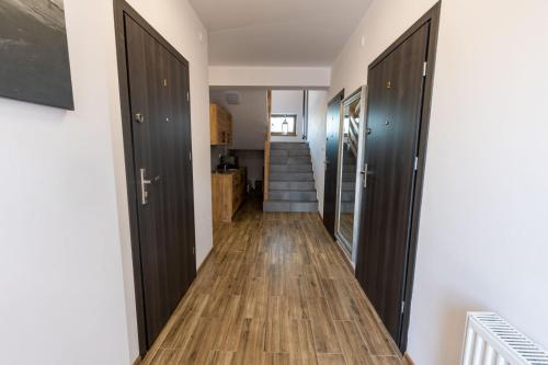 a hallway with black doors and wooden floors at Kwatery PogodneWczasy w Jantarze in Jantar