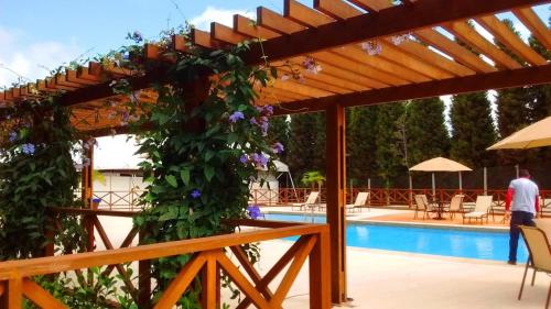 a pergola over a swimming pool with purple flowers at SUÍTE NO VISTA AZUL APART in Pedra Azul