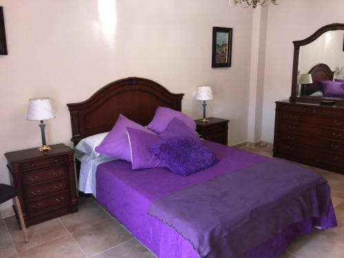 1 dormitorio con 1 cama de color púrpura y 2 mesitas de noche en Lacasadeyolandayedu, en Medina del Campo