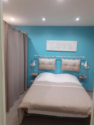 a blue bedroom with a bed and a blue wall at Le paradis d'Alice in Le Molay-Littry