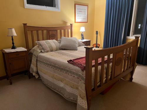 um quarto com uma cama de madeira, 2 mesas de cabeceira e 2 candeeiros. em Luxury 4 bedroom house em Deewhy