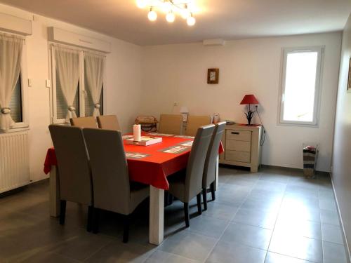 a dining room with a red table and chairs at Les pierres de Lecq in Portbail