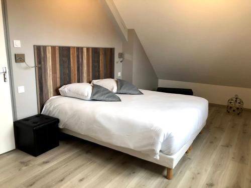 a bedroom with a large white bed with two pillows at Les pierres de Lecq in Portbail