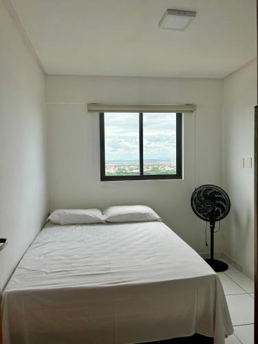 a white bedroom with a bed and a window at Vale Hospedar Orla Apart in Petrolina