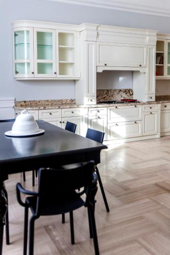 una cocina con armarios blancos, mesa negra y sillas en KASA LUPUS B&B, en Lucera