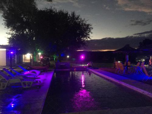 a swimming pool at night with purple lights at Posada La Candelaria in Cosquín