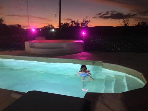 a little girl in a swimming pool at night at Posada La Candelaria in Cosquín
