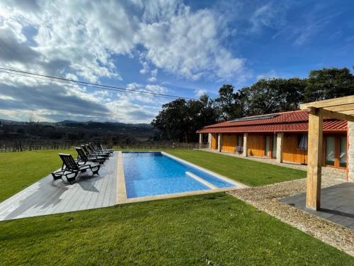 a swimming pool with chairs and a house at Casa de Pelicas - Celorico de Basto in Celorico de Basto