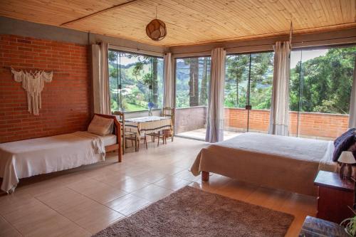 a bedroom with two beds and a table and chairs at Oca Roça in Delfim Moreira