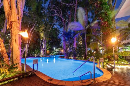 a swimming pool at night with trees and lights at Palm Cove Beachside Apartments - Sea and Mountain Views in Palm Cove